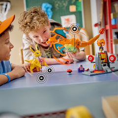 Two children playing with toy dinosaurs at a table in a classroom setting.