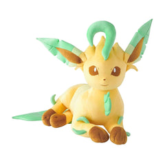 A plush toy of the character Eevee, shown in a sitting position against a solid white background. The plush is primarily a warm pale yellow with mint green leaf accents on its ears, back, and tail, and brown paws and inner ears.